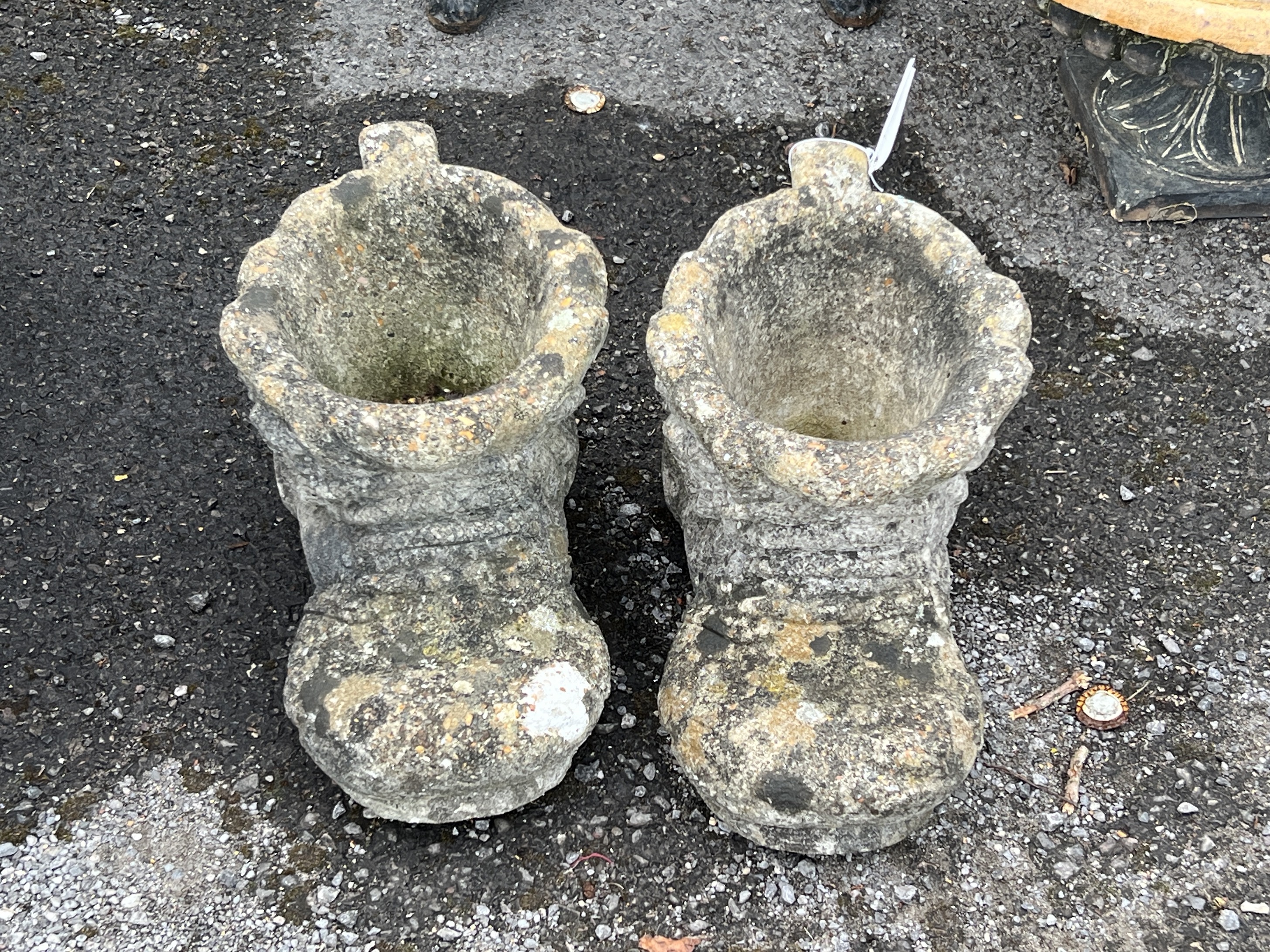 A pair of reconstituted stone garden planters modelled as boots, length 37cm, height 21cm